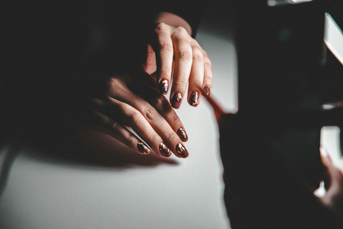 Close-up of hands massaging cuticle oil into nails beside a small amber bottle