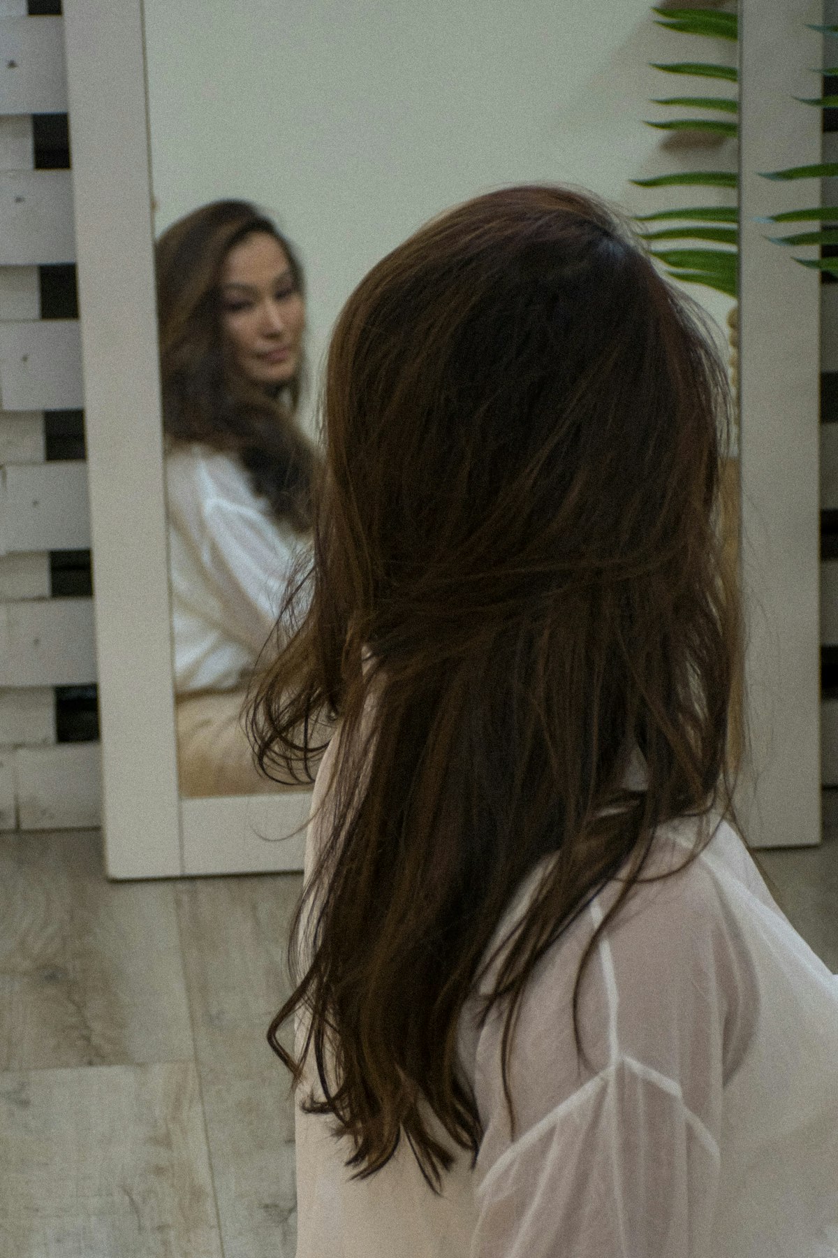 Woman refreshing second-day hair with dry shampoo before leaving home
