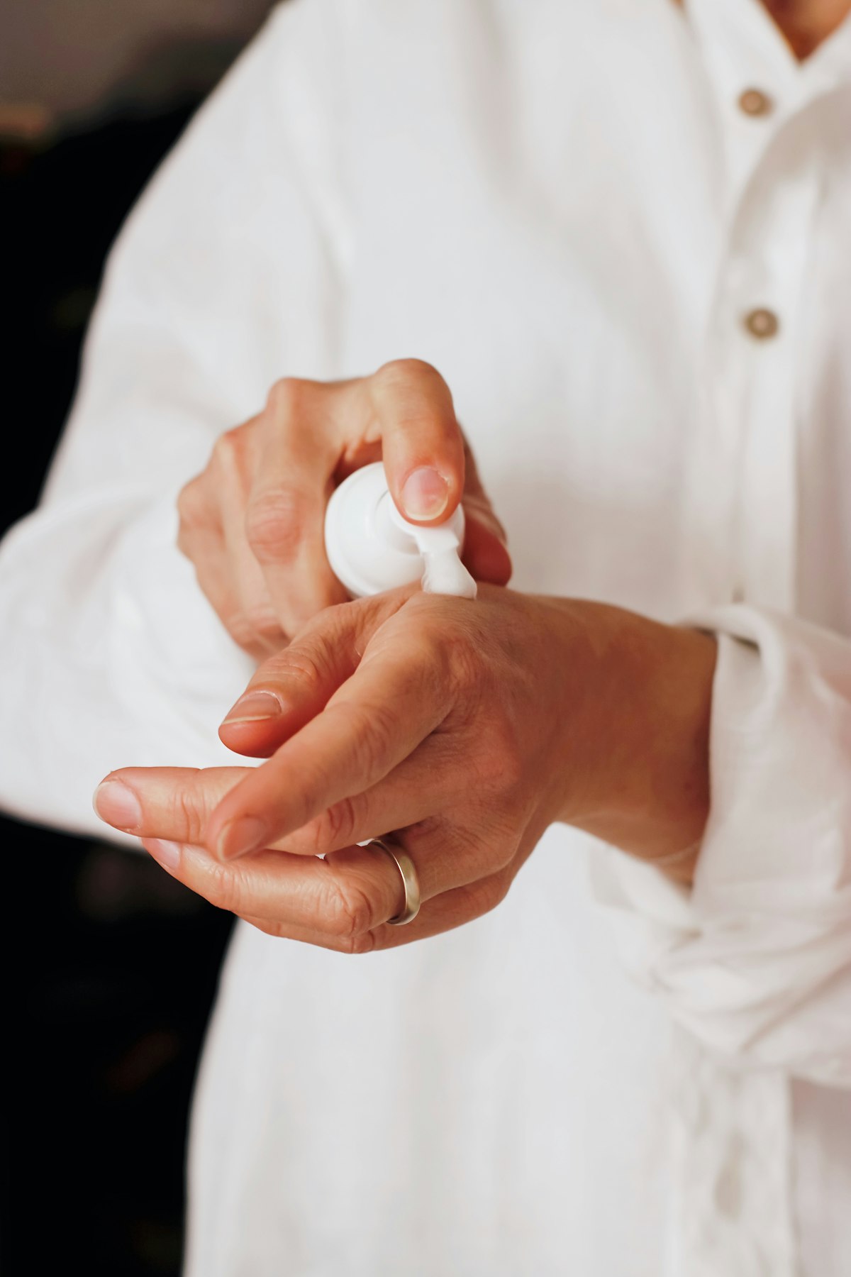 Hands being moisturized with cream beside a kitchen sink on a cold winter day