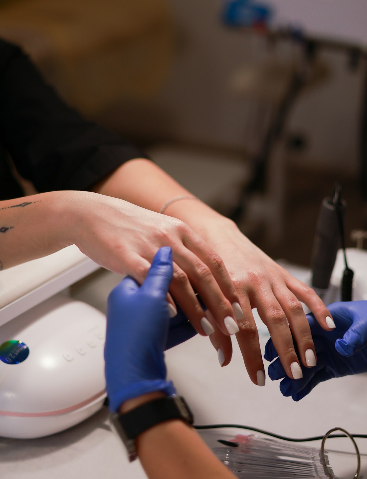Applying glossy top coat over freshly painted red nails at a desk