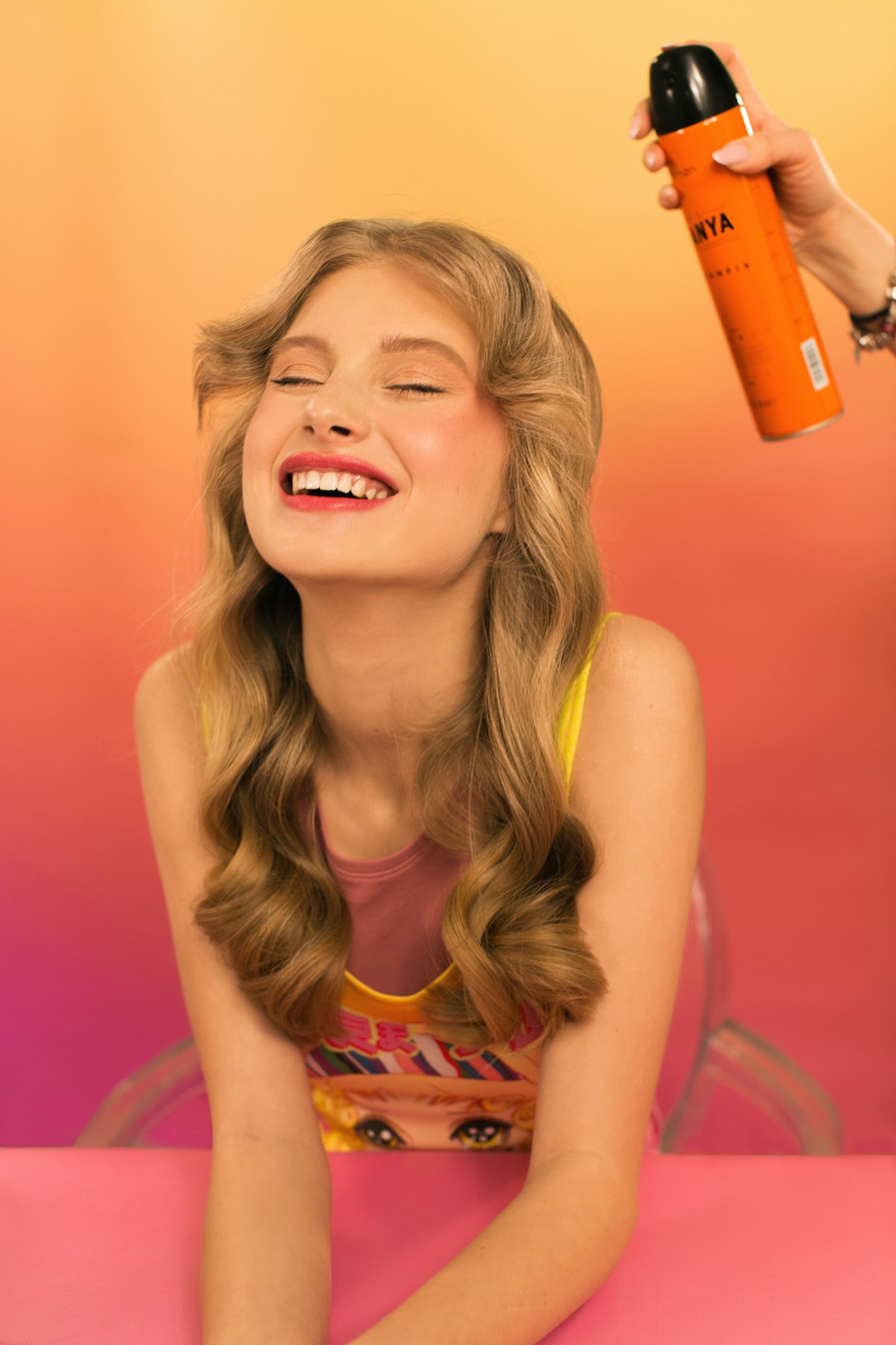 Woman applying leave-in conditioner spray to damp hair at a vanity