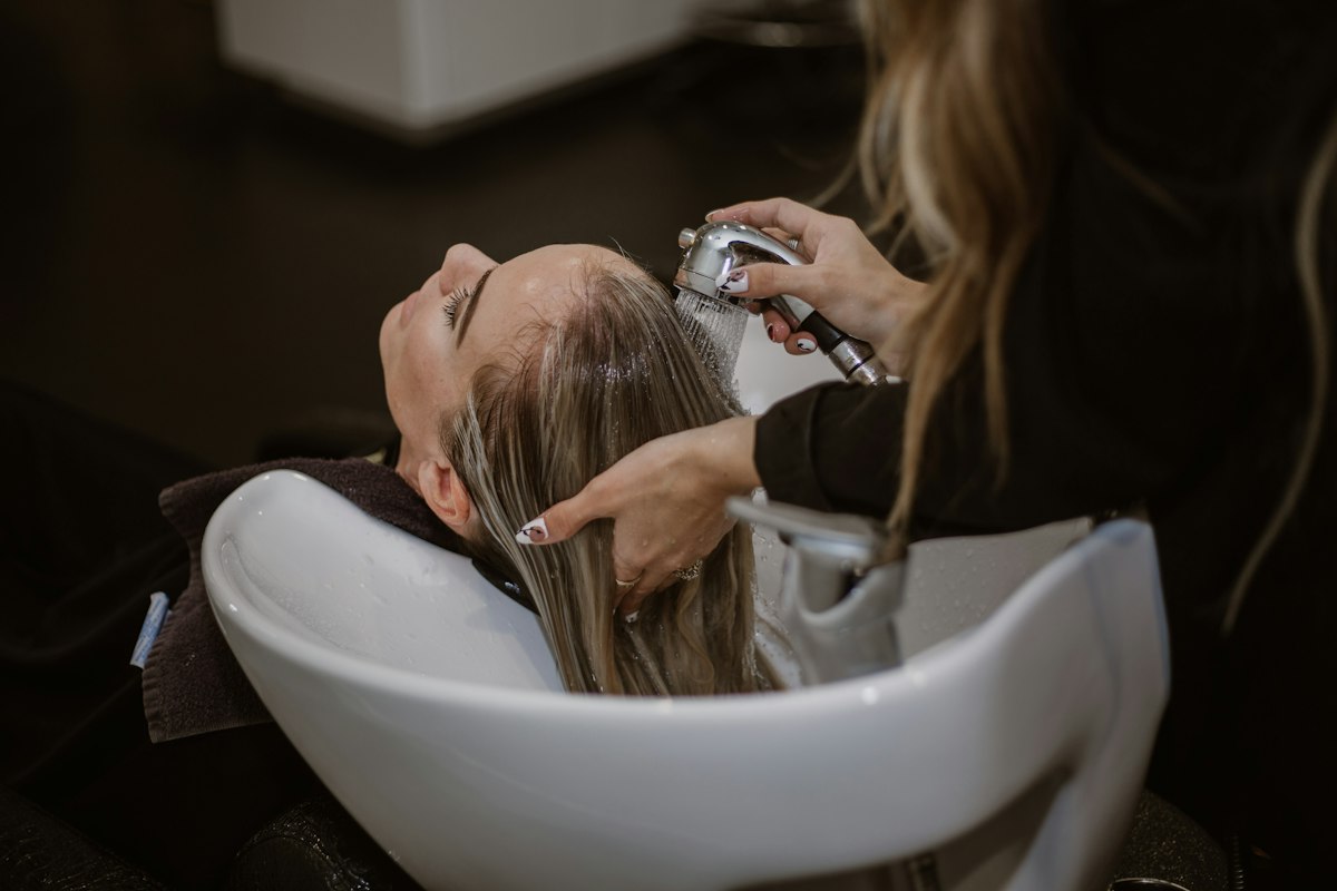 Woman massaging a scalp scrub into parted hair during a wash day routine